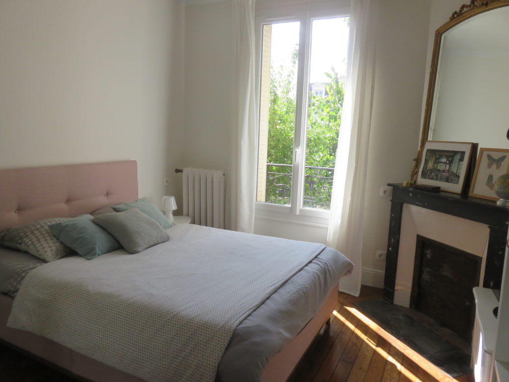 How to renovate an old stone house and reveal its lost charm : the master bedroom with a pink bed, wooden floor and an old period fireplace